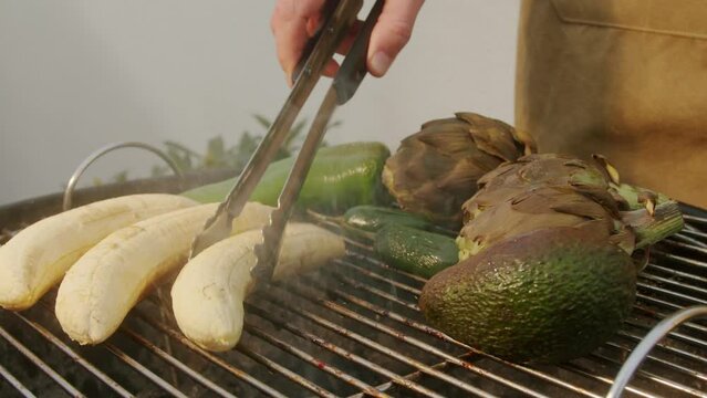 Grilled Banana on fire, latin american vegan grill with avocado and pepper, thai or Ecuadorian Street food. African traditional food on grill. 