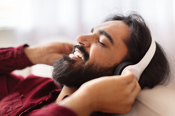 Man lying down with headphones at home
