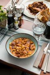 Hearty Breakfast: Pork's Head and Trotters with Tripe and Beans Stew - Traditional Catalan Cuisine in a Rustic Restaurant Ambiance.