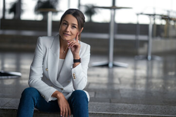 Fototapeta premium Smiling relaxed pretty woman sitting on the steps