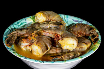 a bowl of large black tiger shrimp marinating to be cooked on the barbecue