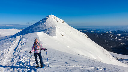 Woman in snowshoes on snow covered mountains of Kor Alps, Lavanttal Alps, Carinthia Styria, Austria. Winter wonderland in Austrian Alps. Ski touring and snow shoe tourism. Tranquil serene atmosphere