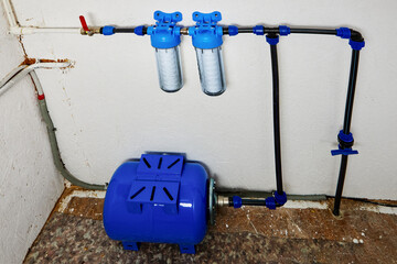 Reverse osmosis diaphragm storage tank, pressure accumulator and cartridges with rope filters in home water supply system in utility room.