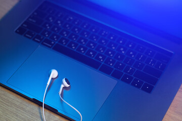 White Earphones lying on the laptop. Modern music concept. Audio technology. Close up photo.