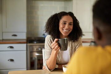 Smiling African woman talking with her husband over coffee at breakfast