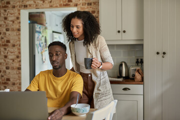 Young multiethnic couple using a laptop in their kitchen in the morning