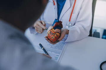 Doctor explaining heart to elderly patient. Doctor explaining the heart model. Doctors pen point to...
