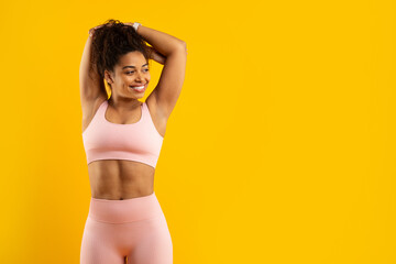 Fototapeta premium Smiling african american woman in workout gear on yellow