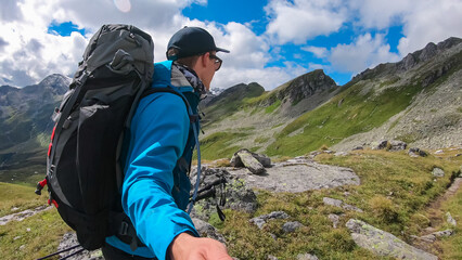 Hiker man on alpine meadow with panoramic view of majestic mount Gamskarlspitz in High Tauern National Park, Carinthia, Austria. Idyllic hiking trail in Austrian Alps. Wanderlust paradise Mallnitz - obrazy, fototapety, plakaty