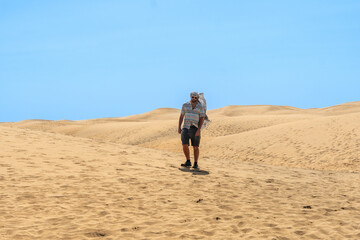 Fototapeta na wymiar Portrait of male tourist in summer walking in the dunes of Maspalomas, Gran Canaria, Canary Islands
