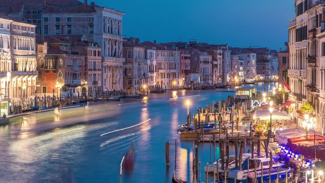 Grand Canal in Venice, Italy day to night transition timelapse. View from above on gondolas and city lights from Rialto Bridge. Beautiful and romantic Italian city on water.