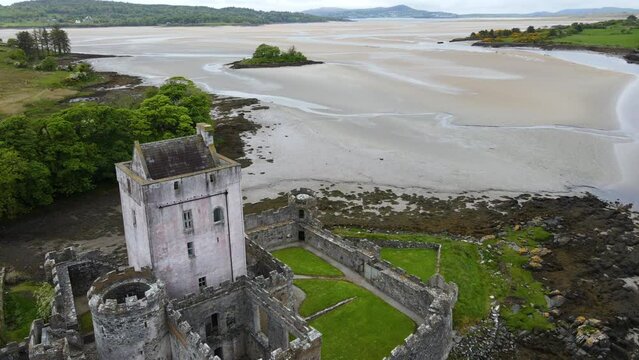 A close up drone shot of an old Irish castle along the sandy coastline, showing the bay in the background. Doe Castle, Co. Donegal, Ireland