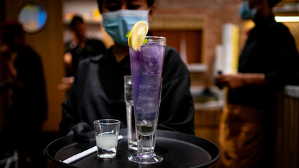 The female waitress brought a Fresh Blue Mojito on a tray