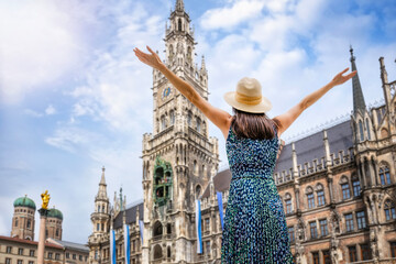 A tourist woman enjoys the beautiful view of the gothic building of the Old town Hall at Marienplatz Square, Munich, Germany  - 774328945