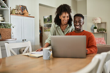 Smiling multiracial couple taking care of their online banking at home