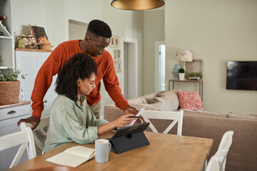 Multiracial couple doing their online banking using a tablet at home