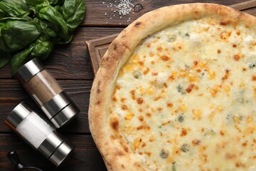 Delicious cheese pizza, basil and spices on wooden table, flat lay