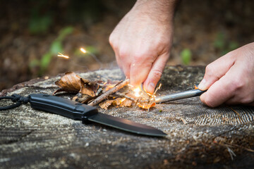 Men hand strarts fire with fire steel in the woods