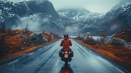 Biker riding a motorbike through a mountain pass in the surrounding fog and snow
