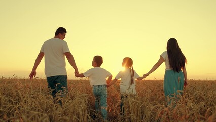Mother father, son daughter enjoying nature together outdoor. Mom, dad, child are go hand in hand. Happy family of farmers with child, are walking on field. Slow motion. People travel. Silhouette