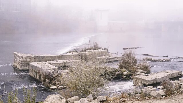 Water flow near stone old plates. Plants in more than. Winter nature. Strong fog.