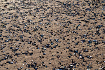 Steiniger Strand mit einzelnen Steinen und Sand an einem Meer als Hintergrund