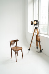 Retro cinema spotlight on tripod and old chair in photo studio on white background