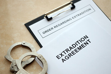 Extradition Agreement and Order Regarding Extradition with handcuffs on table close up