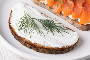 Rye sandwich with cream cheese and salmon on white wooden table