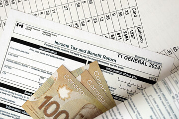 Canadian T1 General tax form Income tax and benefit return lies on table with canadian money bills close up. Taxation and annual accountant paperwork in Canada