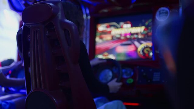 Girl playing racing simulator game in theme park.