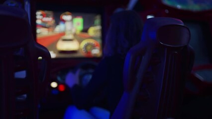 Girl playing racing simulator game in theme park.