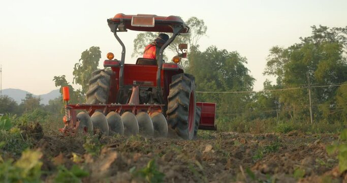 Asian man farmer rides a farm tractor and plowing the agriculture field