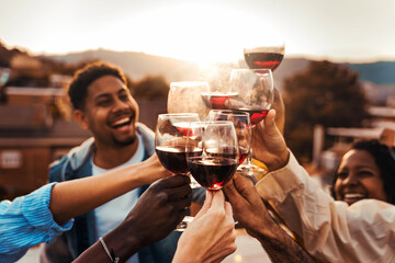 Happy friends toasting red wine glasses at rooftop house party - Men and women having bbq dinner...