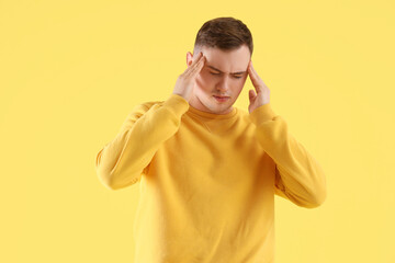 Young man suffering from headache on color background