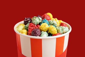 Bucket with sweet colorful popcorn on red background, closeup