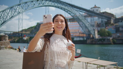 Cheerful blogger holding smartphone recording video at river promenade closeup