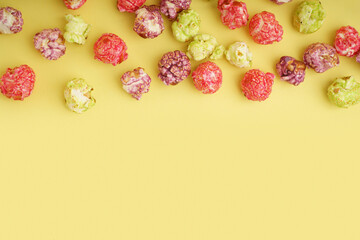 Sweet colorful popcorn on yellow background