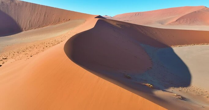 Drone flight over the glowing red sand dunes of the Namib Desert in Sossusvlei early in the morning
