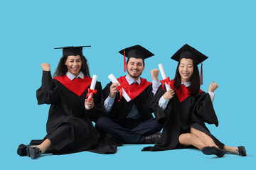 Graduate students with diplomas sitting on blue background