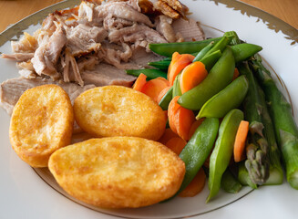 Carrots and snap peas on a plate with roast pork and roast potatos. - 774377504
