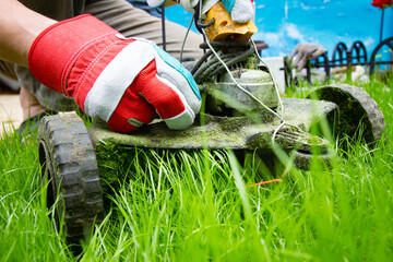 A man and lawnmower grass in the garden - obrazy, fototapety, plakaty