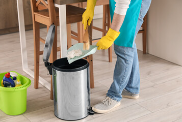Man throwing rubbish into trash bin in kitchen