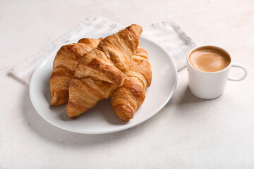 Plate with tasty croissants and cup of coffee on white background