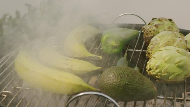 Grilled Banana on fire, latin american vegan grill with avocado and pepper, thai or Ecuadorian Street food. African traditional food on grill. 