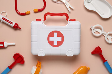 Toy first aid kit with stethoscope, reflex hammer and glasses on beige background. Top view - obrazy, fototapety, plakaty