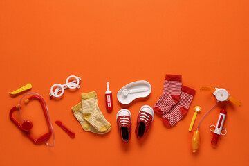 Toy stethoscope with kid's shoes and socks on orange background. Top view