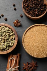 Different spices in bowls on dark gray textured table, flat lay