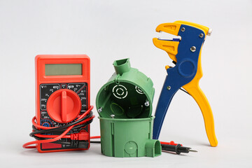 Multimeter, plastic socket boxes and wire stripper on light background