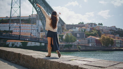 Happy tourist walking river bank cityscape back view. Joyful woman raising arms